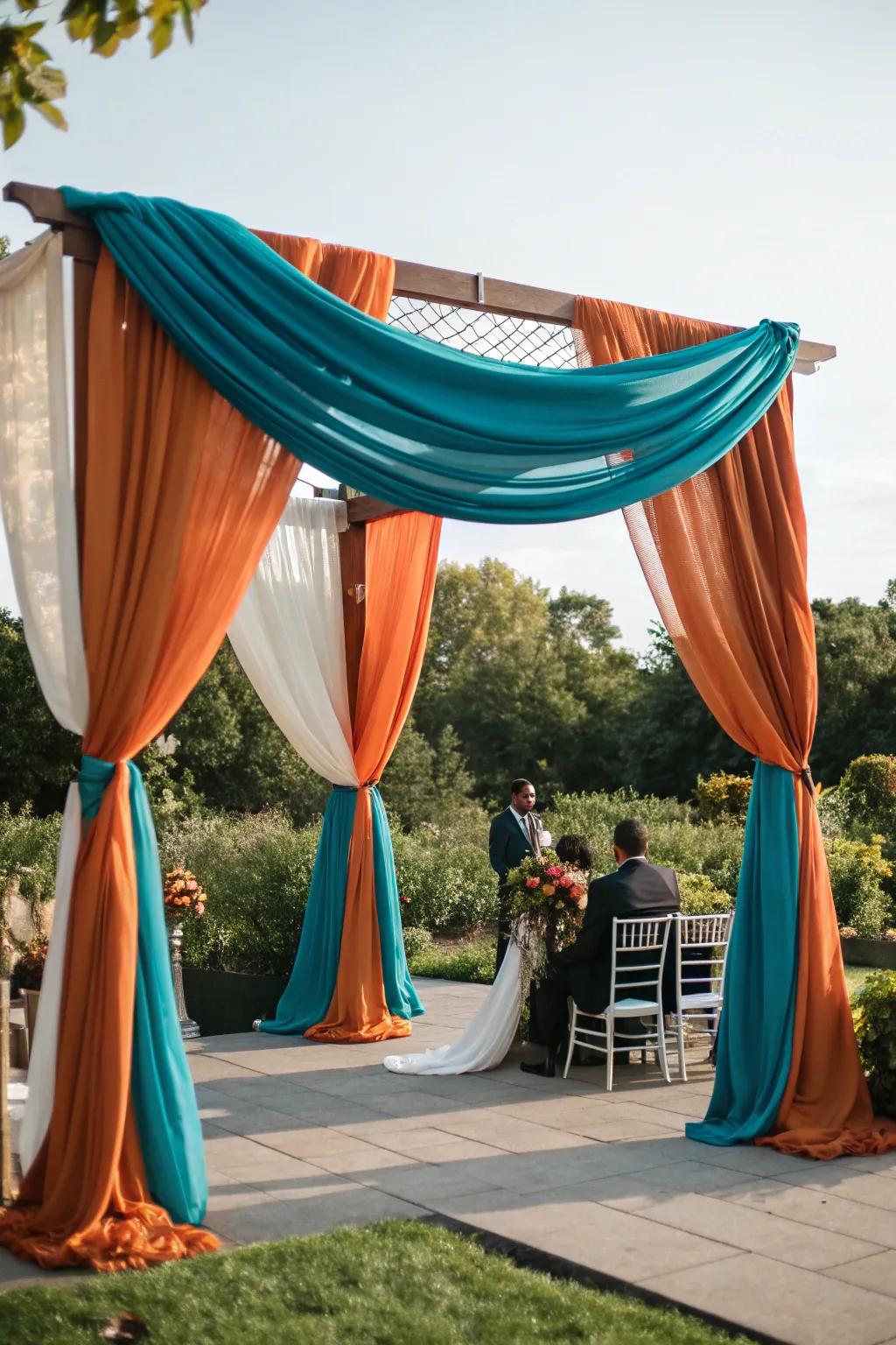 A ceremony arch draped in stunning teal and burnt orange fabrics.