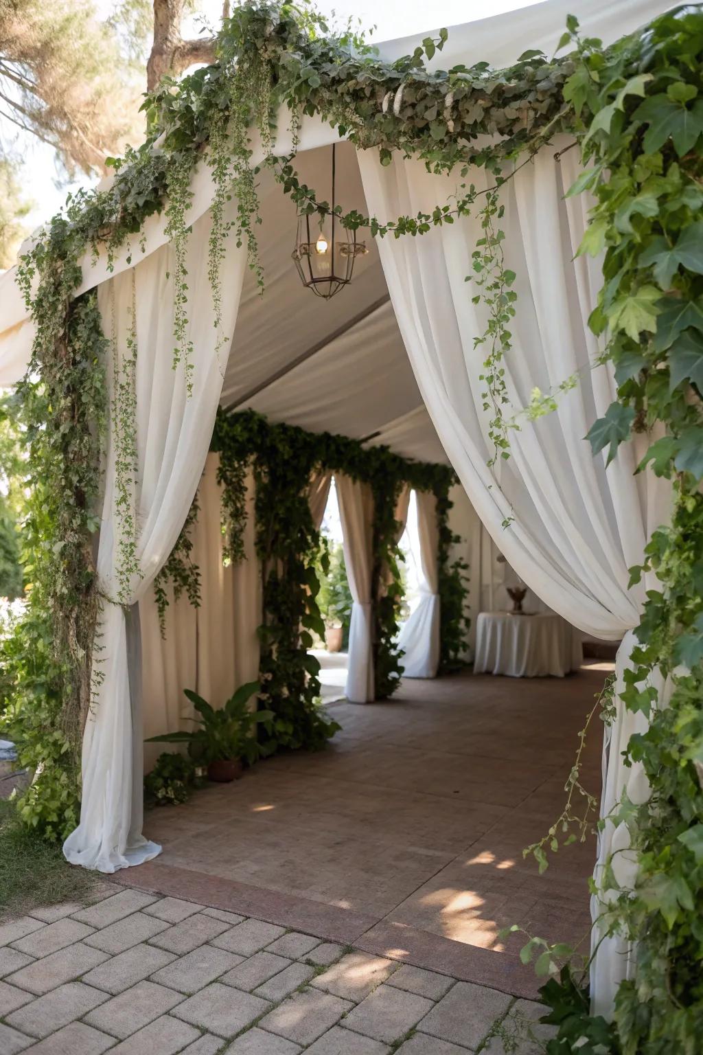 A grand tent entrance adorned with elegant greenery and sheer fabric.